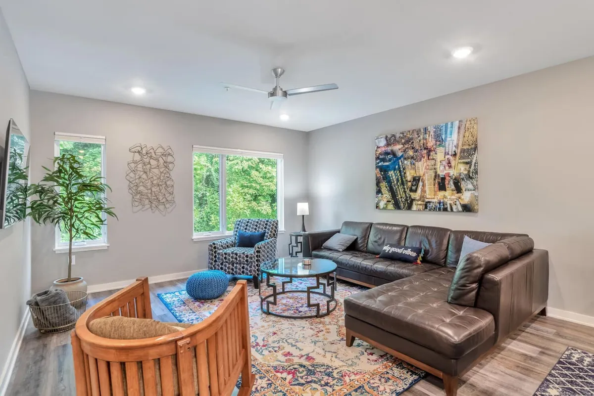 This image features a large sectional sofa paired with a colorful armchair, a coffee table, and vibrant wall art. The arrangement is spacious and inviting, perfect for group gatherings or relaxing before a night out.