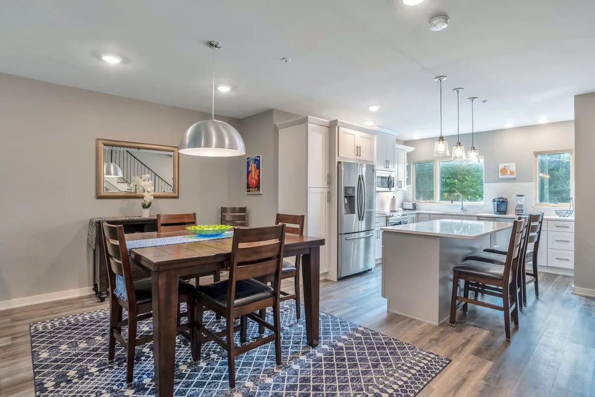 A cozy dining area with a family-sized table, kitchen island, and vibrant decorative artwork. The space is designed for shared meals, casual gatherings, and culinary bonding moments.